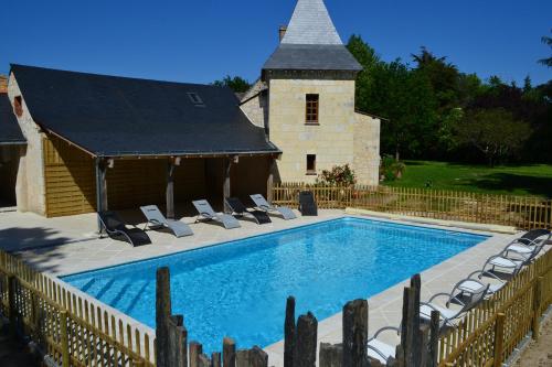 - une piscine avec des chaises et une église dans l'établissement Maison d'Hôtes La Chouanniere, à Brion
