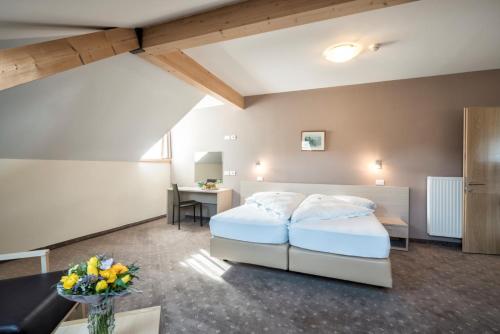 a hotel room with two beds and a desk at Hotel Weingarten in Caldaro