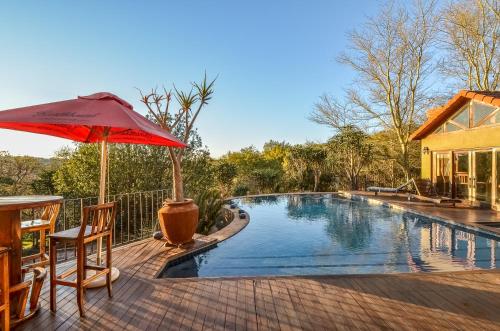 a pool with an umbrella and a table and chairs at Afrique Boutique Ruimsig in Roodepoort