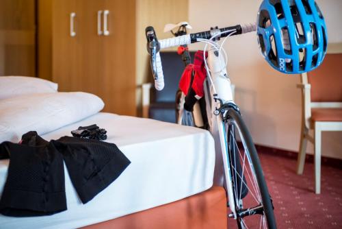 a bike parked next to a bed with a helmet on it at Hotel Weingarten in Caldaro