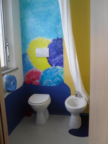 a bathroom with a toilet and a painting on the wall at Hostel San Marino in San Marino
