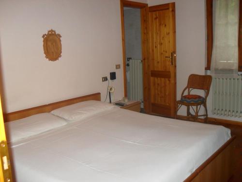 Albergo La Genzianella في بيلاجيو: غرفة نوم بسرير ابيض وكرسي