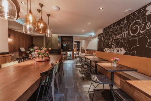 un restaurant avec de longues tables et chaises en bois dans l'établissement Mr. Jordaan, à Amsterdam