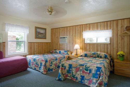2 łóżka w pokoju z drewnianymi ścianami w obiekcie Lazy J Ranch Motel w mieście Three Rivers