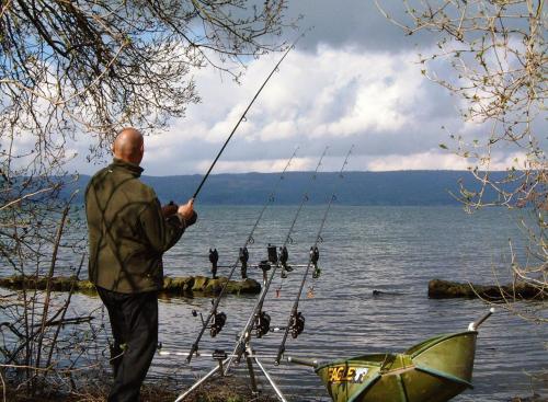 a man holding a fishing rod on a lake at Casa "Le tre Muse" in Deruta