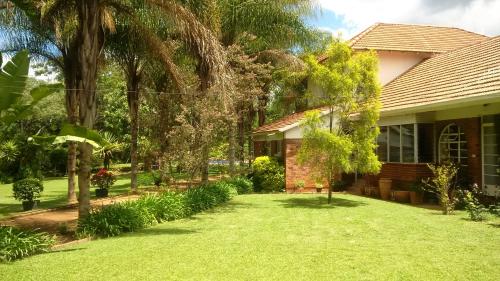a house with a yard with green grass and trees at Hillside Manor in Bulawayo