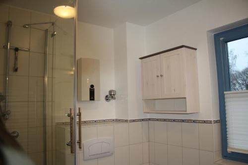 ein Bad mit einer Dusche und einem Waschbecken sowie einem Schrank in der Unterkunft Ferienwohnung Urte in Putgarten , Kap Arkona Rügen in Putgarten