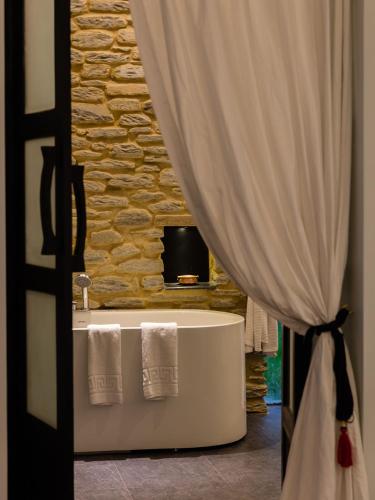 a bathroom with a tub and a television and a curtain at The Pavilions Himalayas The Farm in Pokhara