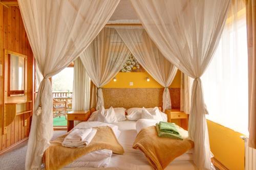 ヘーヴィーズにあるKaktusz Villa Hevizのベッドルーム(白いカーテン付きの天蓋付きベッド1台付)