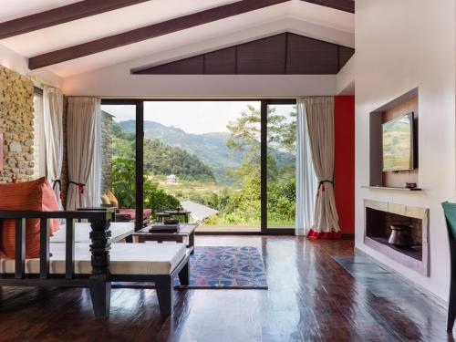 a living room with a fireplace and large windows at The Pavilions Himalayas The Farm in Pokhara