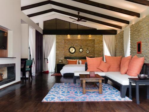a living room with a couch and a bed and a fireplace at The Pavilions Himalayas The Farm in Pokhara