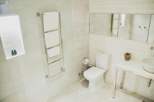 Baño blanco con aseo y lavamanos en Cosmopolitano Hotel Boutique, en Santa Cruz de la Sierra