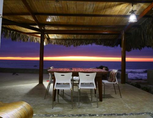 einen Tisch und Stühle unter einem Pavillon am Strand in der Unterkunft Casa Gonzales Gonzales in Canoas De Punta Sal