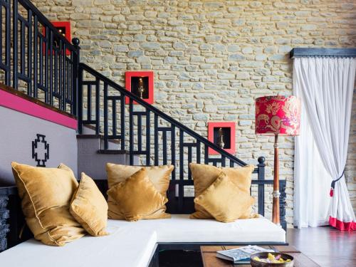 a couch with pillows in a room with a staircase at The Pavilions Himalayas The Farm in Pokhara