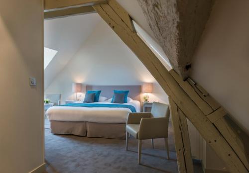 a bedroom with a king sized bed in a attic at H&ocirc;tel Aux Vieux Remparts, The Originals Relais in Provins
