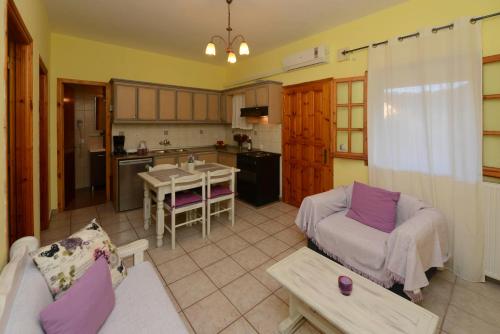 a living room with a couch and a kitchen at Olga's Garden Apartments in Almiros Beach