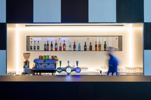 a bar with a shelf with bottles on it at ibis Styles Basel City in Basel