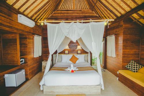 a bedroom with a white bed with a canopy at Dini D'Nusa Lembongan in Nusa Lembongan