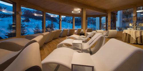 a restaurant with white chairs and tables and windows at Hotel Baita Montana in Livigno