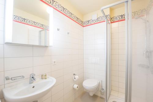 a bathroom with a toilet and a sink and a shower at Parkhotel Muldental in Colditz