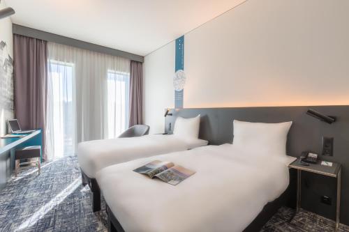 a hotel room with two beds and a desk at ibis Styles Basel City in Basel