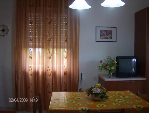 PizzoにあるVillino mare Anitaのテーブル、テレビ、カーテン付きの部屋