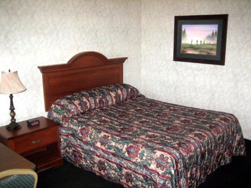 a hotel room with a bed and a table with a lamp at Fair Motel in Upper Saddle River