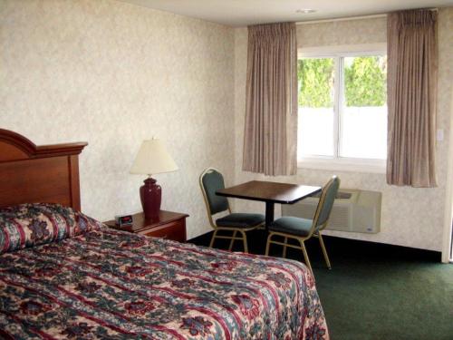 a hotel room with a bed and a table and a window at Fair Motel in Upper Saddle River