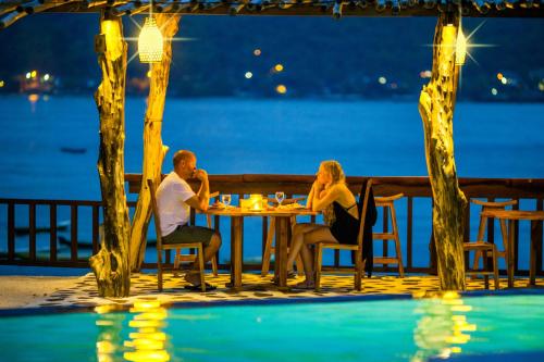 a couple sitting at a table by the water at night at Dini D'Nusa Lembongan in Nusa Lembongan