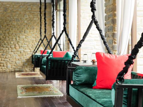 a swing room with a green couch and a red pillow at The Pavilions Himalayas The Farm in Pokhara