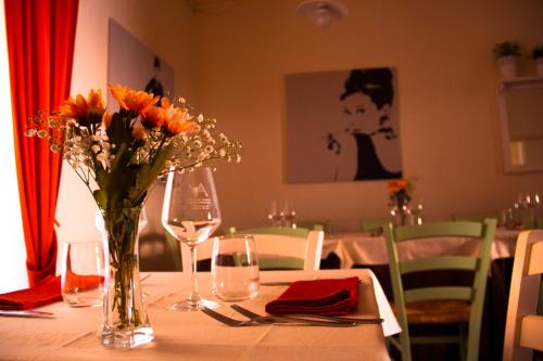 a table with a vase of flowers and wine glasses at IL Borgo Ristorante Pizzeria Camere in Acquapendente