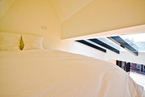 1 dormitorio con cama blanca y ventana en Fantastic Bright Penthouse, en Ámsterdam