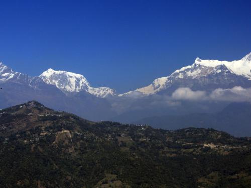 a mountain range with snow capped mountains in the background at The Pavilions Himalayas The Farm in Pokhara