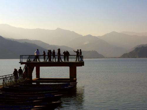 a group of people standing on a pier in the water at The Pavilions Himalayas The Farm in Pokhara
