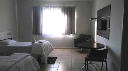 a bedroom with a bed and a table and a window at Gold - Inn Hotel in Apiaí