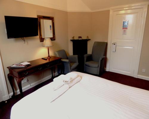 a hotel room with a bed and a television at Tulloch Castle Hotel ‘A Bespoke Hotel’ in Dingwall
