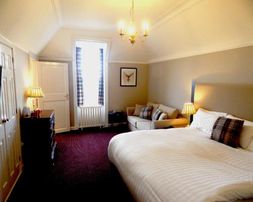 a hotel room with a bed and a couch at Tulloch Castle Hotel ‘A Bespoke Hotel’ in Dingwall