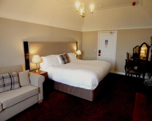 a hotel room with a large bed and a couch at Tulloch Castle Hotel ‘A Bespoke Hotel’ in Dingwall