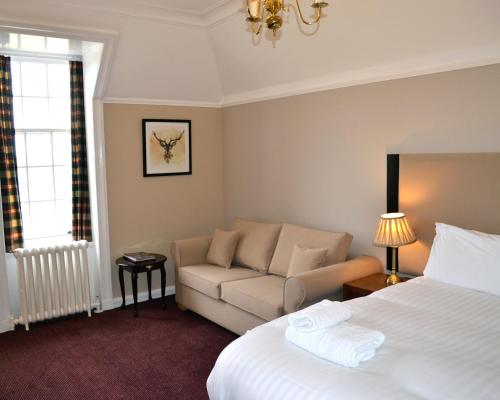 a hotel room with a bed and a couch at Tulloch Castle Hotel ‘A Bespoke Hotel’ in Dingwall