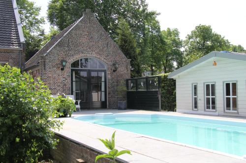 a swimming pool in front of a house at De Oude Pastorie in Netersel