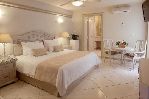 グアダラハラにあるHotel & Suites Quinta Magnaのベッドルーム1室(大型ベッド1台、テーブル、椅子付)