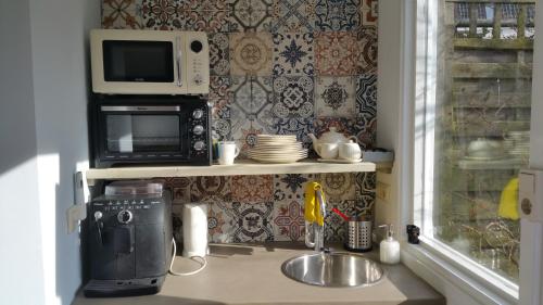 a small kitchen with a microwave and a sink at In de Stad, en rustig als op het Platteland in Middelburg