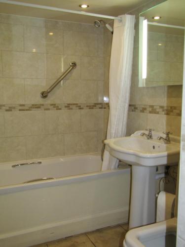 a bathroom with a sink and a tub and a toilet and a bath tub at The Kilcot Inn in Newent