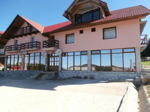 a house with glass windows and a red roof at Pensiunea Bradet - Padis in Padis