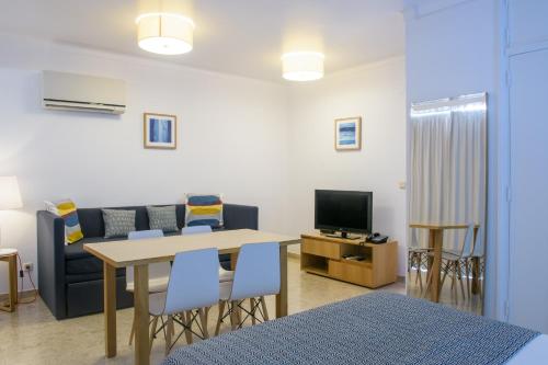 a living room with a table and chairs and a tv at Apartamentos Dunamar in Vila Nova de Milfontes