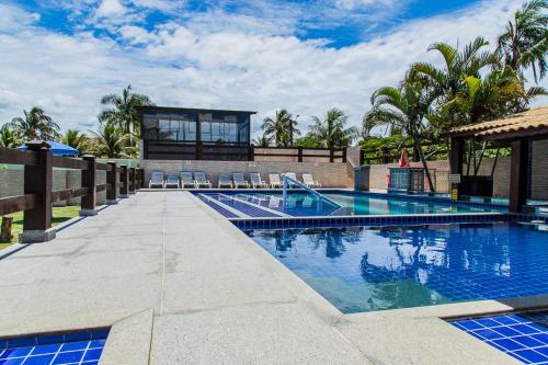 a swimming pool with a villa in the background at Hotel Pousada Recanto in Ilha Comprida