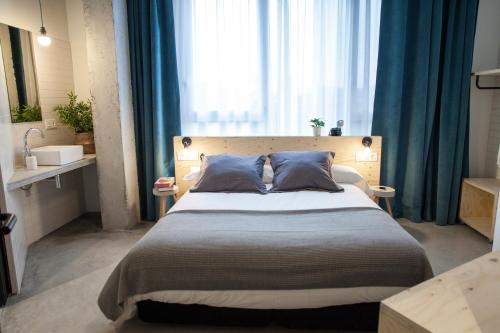a bedroom with a large bed with blue curtains at Talo Urban Rooms in Donostia-San Sebastián