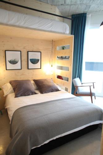 a bedroom with a large bed and a chair at Talo Urban Rooms in Donostia-San Sebastián