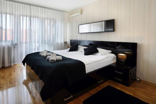 1 dormitorio con 1 cama grande con manta negra en Apartment Check In Zagreb Maksimir-free parking, en Zagreb
