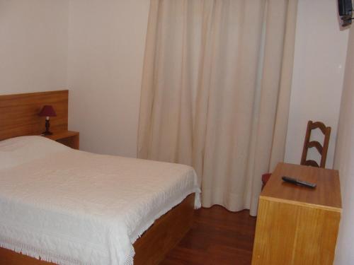 a bedroom with a bed and a table and a window at Alojamento Local Lindo Verde in Vieira do Minho